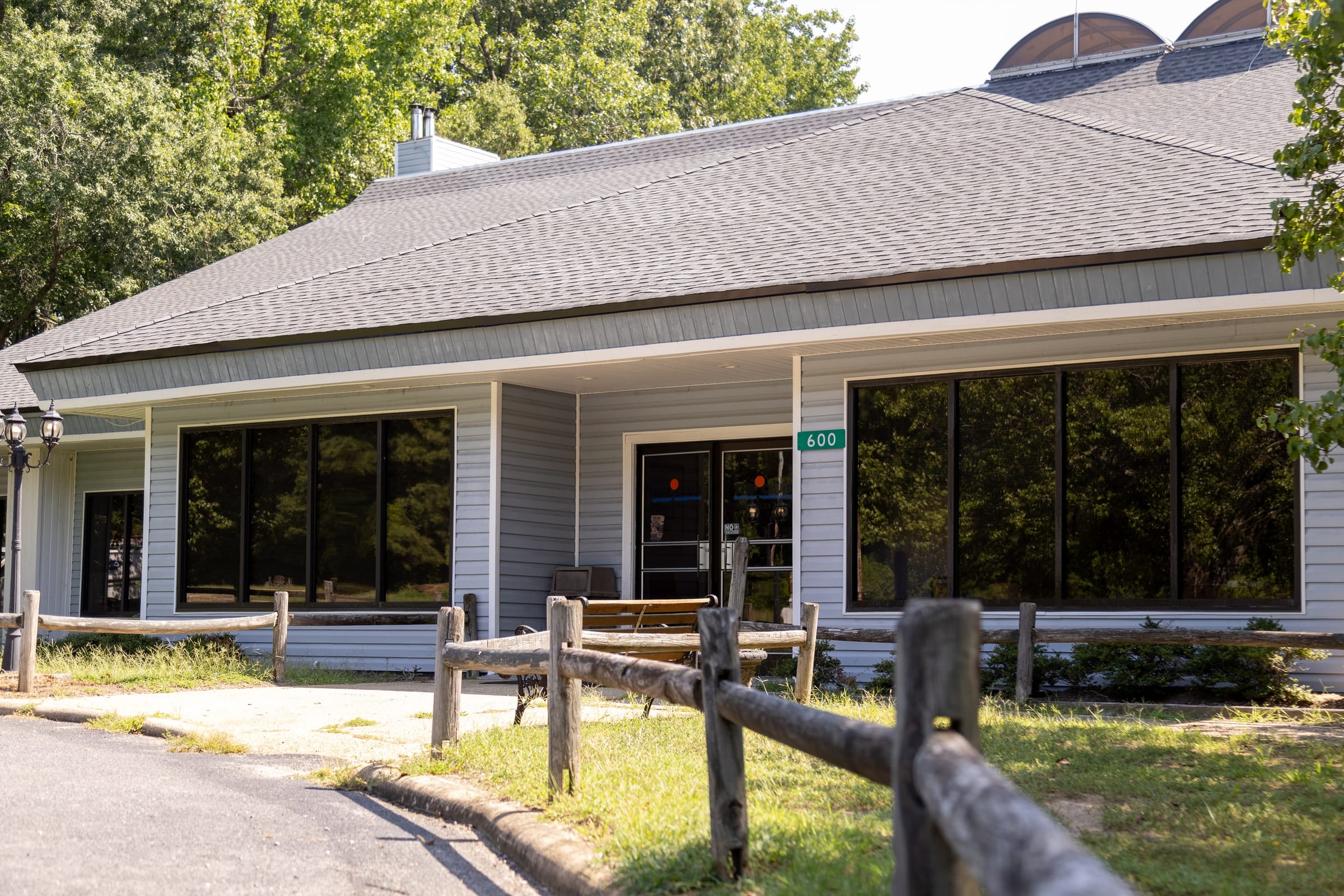 Gray the Boulder House entrance with glass front behind the split-rail fence