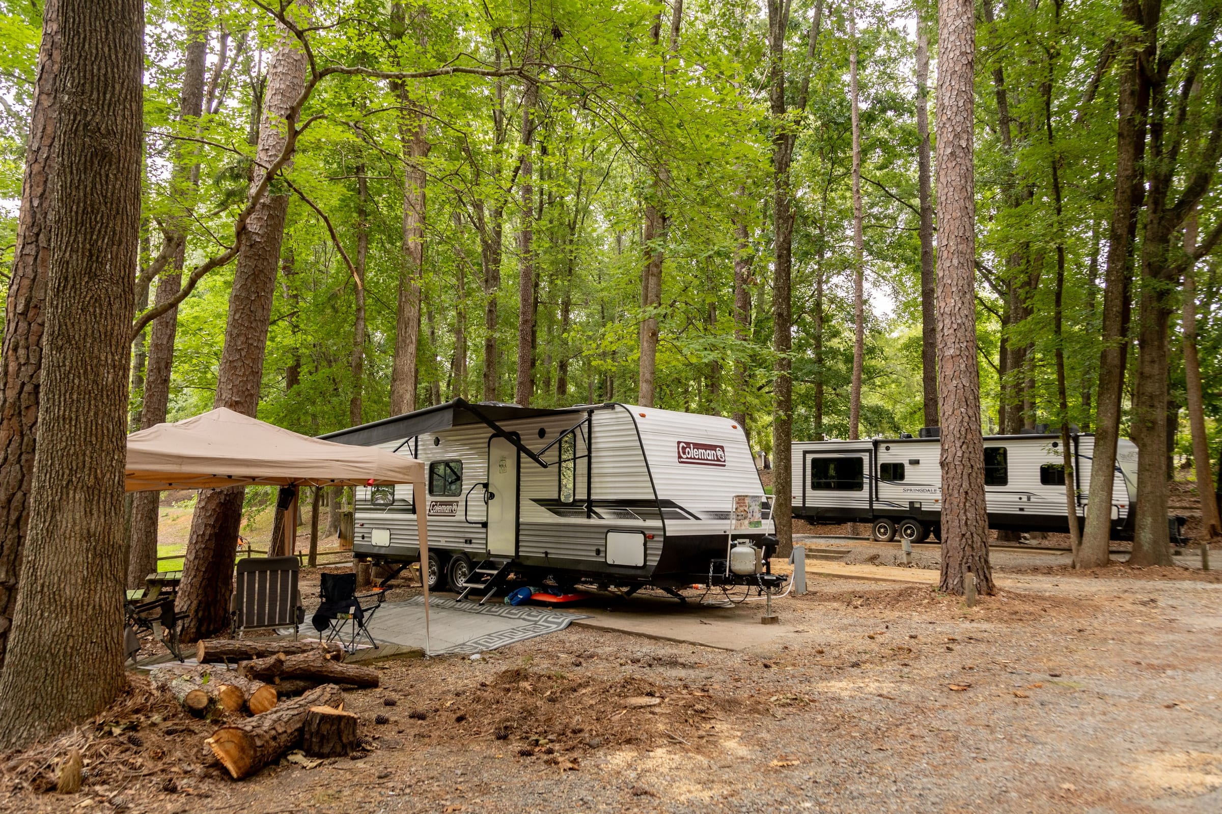 Travel trailer with awning canopy set up on a wooded site