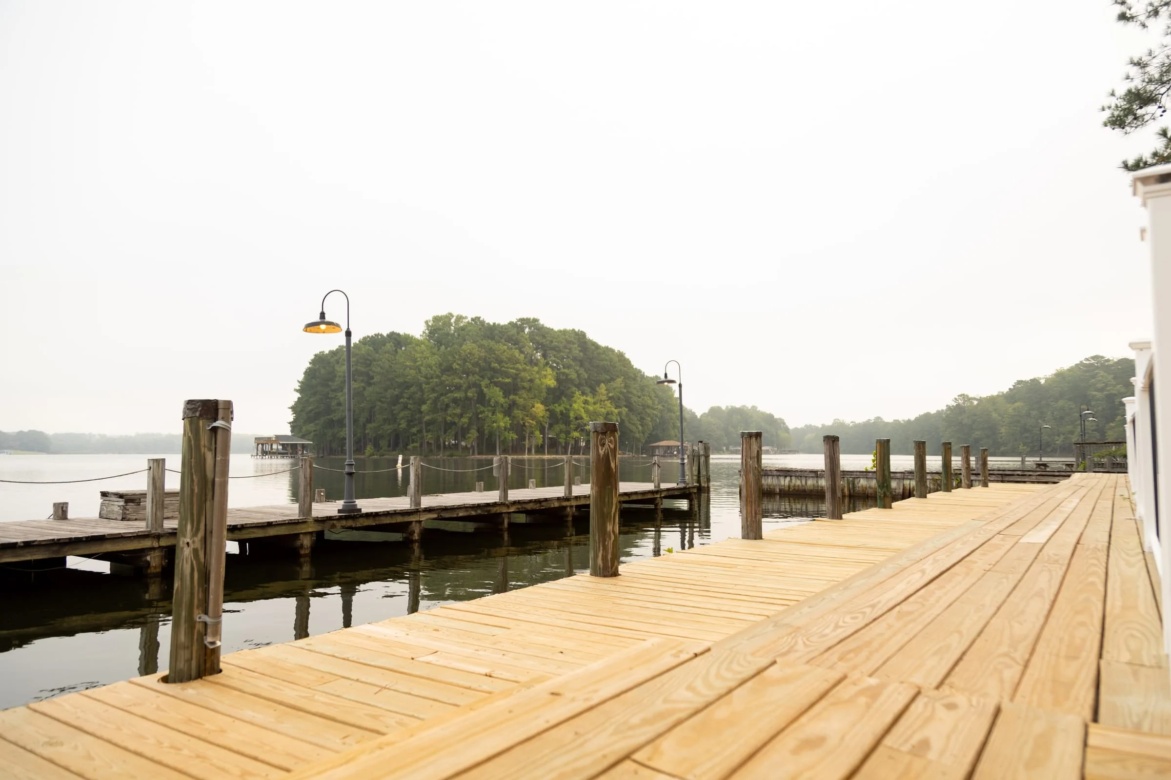 Fresh-cut lumber decking on rebuilt marina slips with lamp posts down the dock